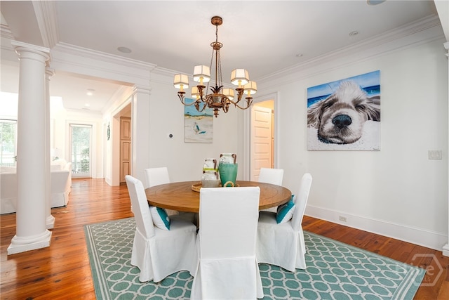 dining area featuring ornate columns, wood finished floors, a chandelier, ornamental molding, and baseboards