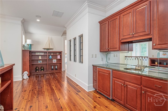 kitchen featuring open shelves, dark stone countertops, light wood-type flooring, a sink, and baseboards