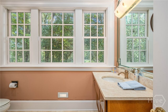 half bathroom with vanity, toilet, and healthy amount of natural light