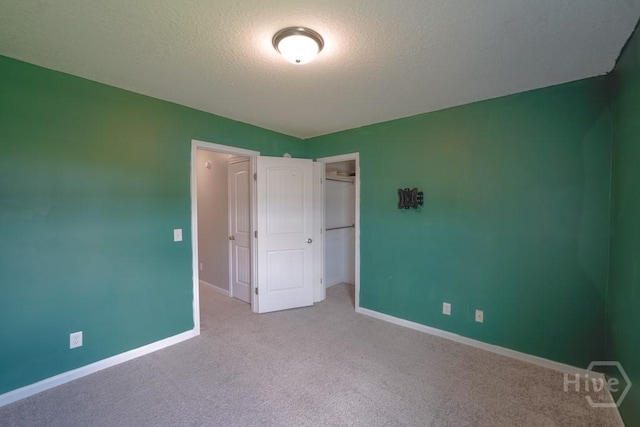 24 Daylily Ct, Hinesville, GA 31313 - unfurnished bedroom featuring carpet flooring, baseboards, a textured ceiling, a closet, and a walk in closet