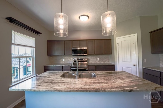 24 Daylily Ct, Hinesville, GA 31313 - kitchen with appliances with stainless steel finishes, backsplash, a sink, a textured ceiling, and a kitchen island with sink