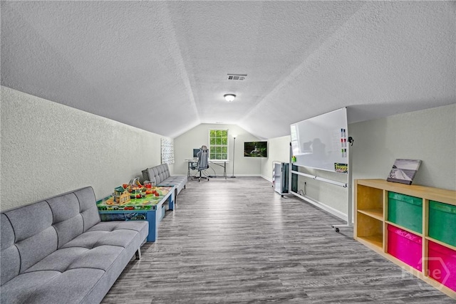 game room with wood finished floors, vaulted ceiling, a textured ceiling, a textured wall, and baseboards