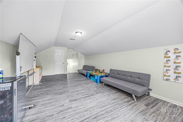 recreation room featuring wood finished floors, vaulted ceiling, and baseboards