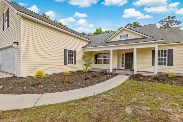 view of front of house featuring covered porch, a garage, and a shingled roof