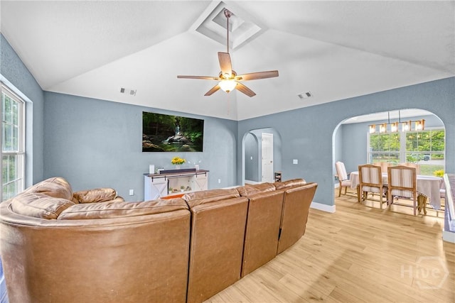 living area featuring arched walkways, light wood-type flooring, lofted ceiling, healthy amount of natural light, and a ceiling fan