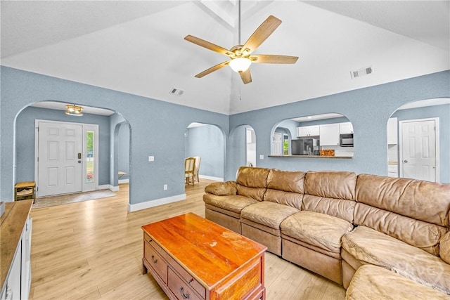 living room featuring a ceiling fan, arched walkways, light wood-type flooring, high vaulted ceiling, and baseboards
