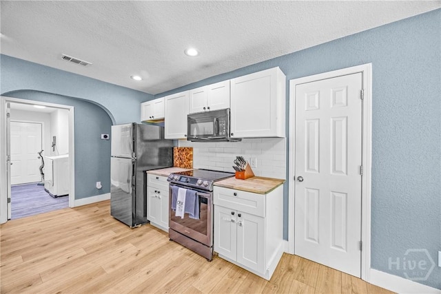 kitchen featuring black appliances, decorative backsplash, washer / dryer, white cabinets, and light wood finished floors