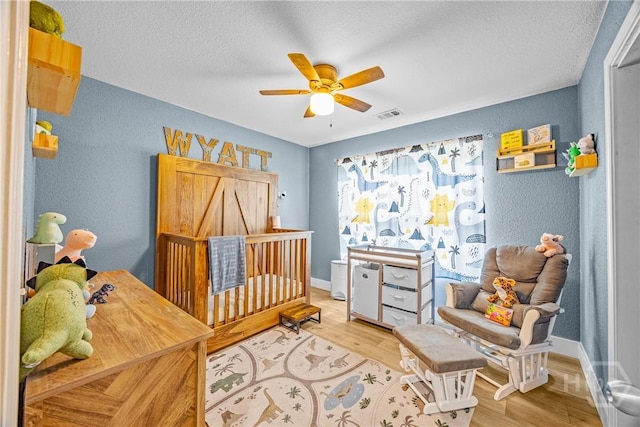 bedroom featuring a textured wall, wood finished floors, a textured ceiling, baseboards, and a ceiling fan