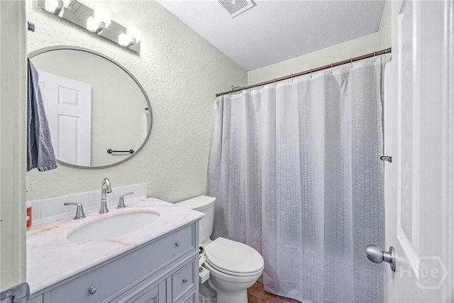 bathroom with a textured wall, toilet, vanity, curtained shower, and wood finished floors