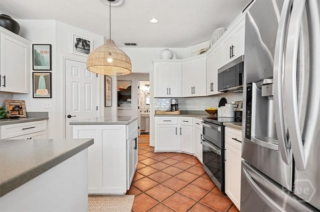 kitchen with appliances with stainless steel finishes, tasteful backsplash, white cabinets, a kitchen island, and pendant lighting