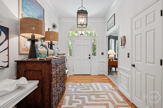 entryway with light wood finished floors and crown molding