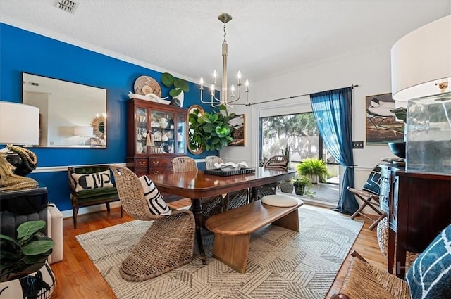 dining space featuring a chandelier, wood finished floors, and crown molding