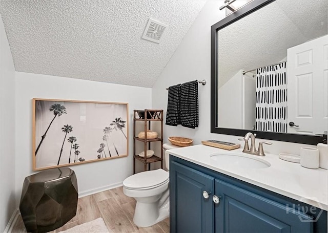 bathroom featuring a textured ceiling, lofted ceiling, wood finished floors, toilet, and vanity