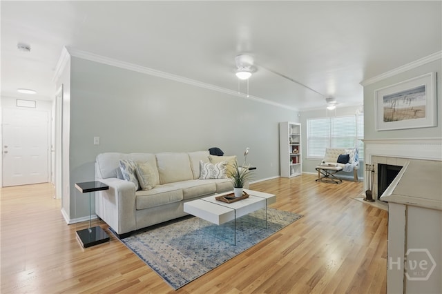 living area with crown molding, baseboards, light wood-type flooring, a tile fireplace, and ceiling fan