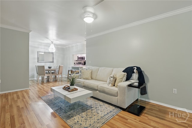 living area with light wood-type flooring, baseboards, and ornamental molding