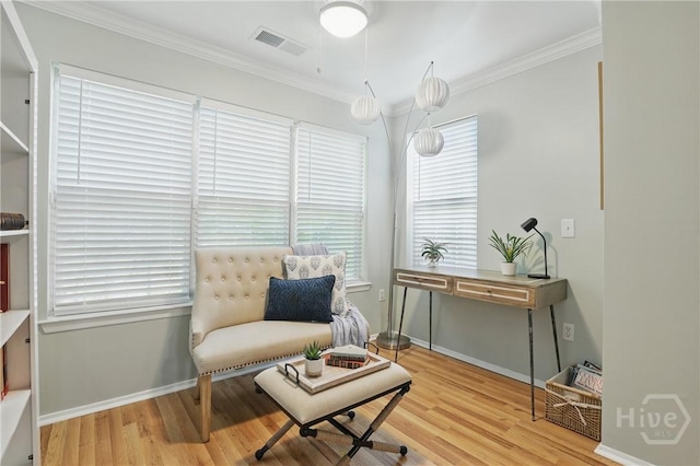 sitting room with wood finished floors, ornamental molding, and baseboards