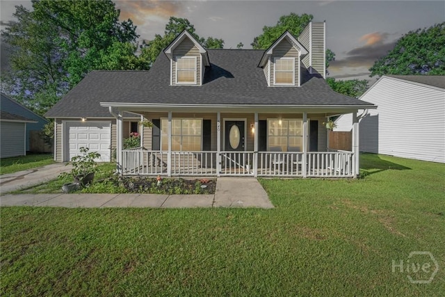 new england style home featuring a porch, a garage, a chimney, a front yard, and driveway