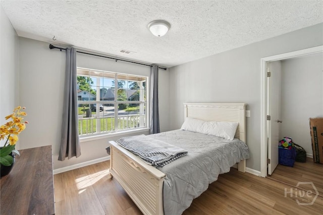 bedroom featuring wood finished floors, baseboards, and a textured ceiling