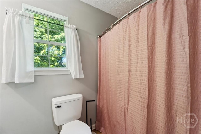 full bath with toilet and a textured ceiling