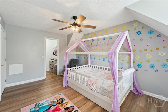 bedroom with wallpapered walls, baseboards, wood finished floors, a textured ceiling, and ceiling fan