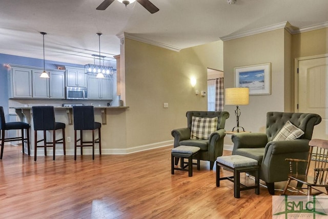 living area with crown molding, ceiling fan, light wood-style floors, and baseboards