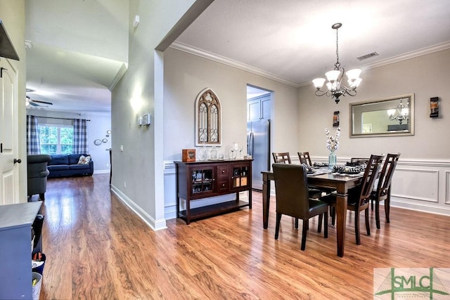 dining room with a chandelier, light wood-type flooring, ornamental molding, ceiling fan, and baseboards