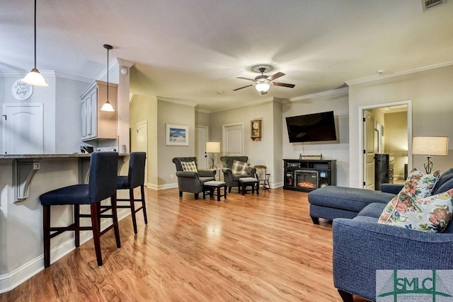 living room with ceiling fan, light wood-type flooring, crown molding, and baseboards