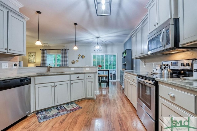 kitchen featuring stainless steel appliances, a sink, healthy amount of natural light, a peninsula, and crown molding