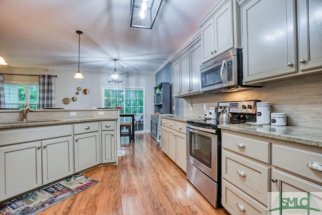 kitchen featuring stainless steel appliances, a sink, light wood-type flooring, backsplash, and crown molding