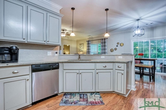 kitchen with dishwasher, a sink, a peninsula, ornamental molding, and light wood-style floors
