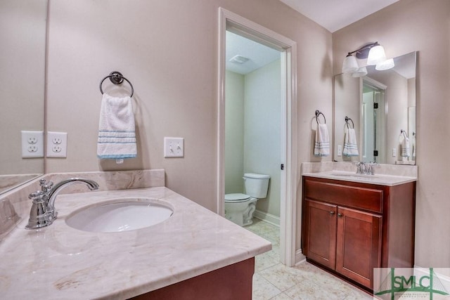 bathroom featuring two vanities, toilet, and tile patterned floors