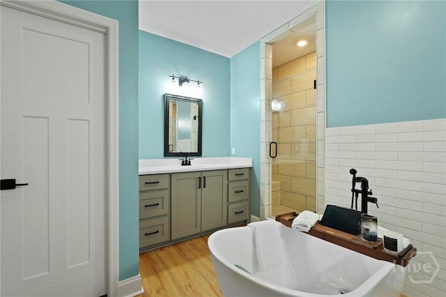 full bathroom with a stall shower, a soaking tub, vanity, and wood finished floors