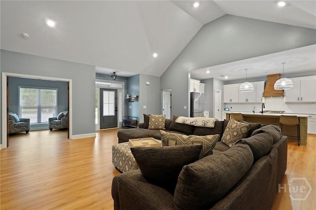 living area with high vaulted ceiling, recessed lighting, and light wood-type flooring