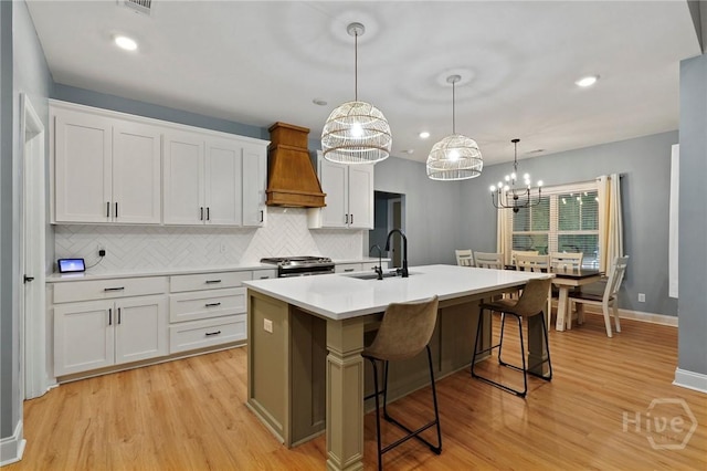 kitchen featuring a sink, custom range hood, tasteful backsplash, light wood-style flooring, and recessed lighting