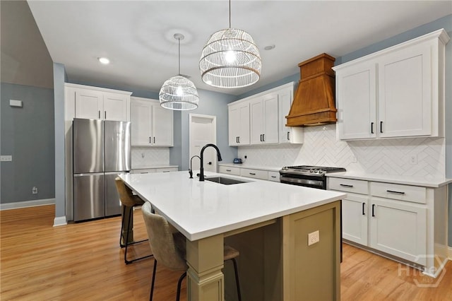 kitchen featuring stainless steel appliances, a sink, premium range hood, white cabinetry, and backsplash