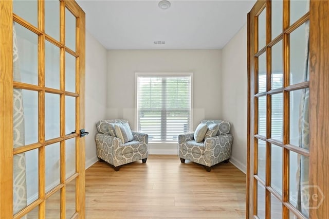 living area featuring french doors, light wood-type flooring, and baseboards