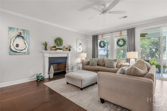 living area with ornamental molding, baseboards, wood finished floors, a fireplace with flush hearth, and a ceiling fan