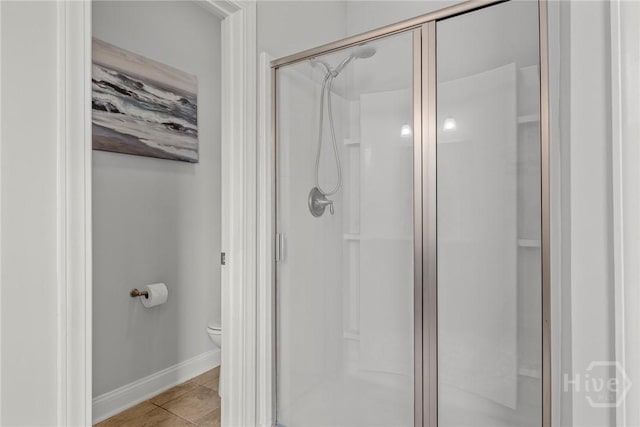full bathroom featuring a stall shower, toilet, baseboards, and tile patterned flooring