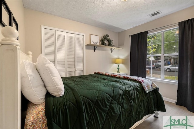 bedroom featuring a textured ceiling, a closet, baseboards, and wood finished floors