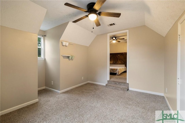 additional living space featuring ceiling fan, a textured ceiling, lofted ceiling, carpet flooring, and baseboards