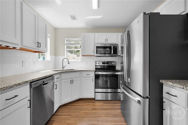 2 Mclaughlin Ct, Savannah, GA 31419 - kitchen featuring stainless steel appliances, a sink, a textured ceiling, white cabinetry, and wood finished floors