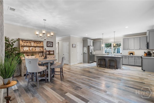 dining space with a chandelier, light wood-type flooring, ornamental molding, baseboards, and recessed lighting