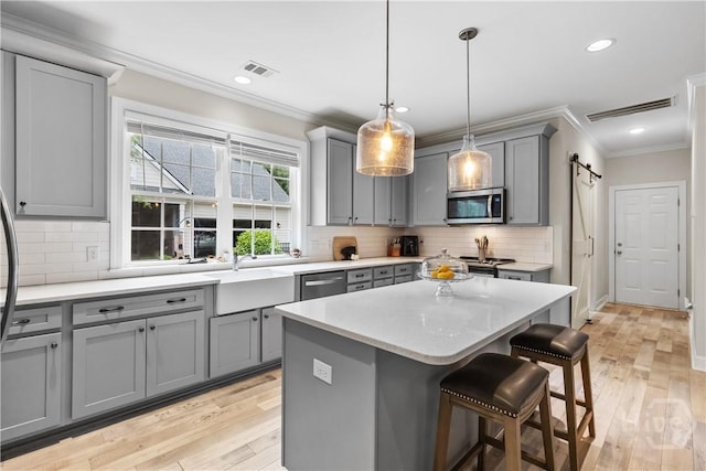 kitchen with gray cabinets, appliances with stainless steel finishes, crown molding, a kitchen breakfast bar, and recessed lighting