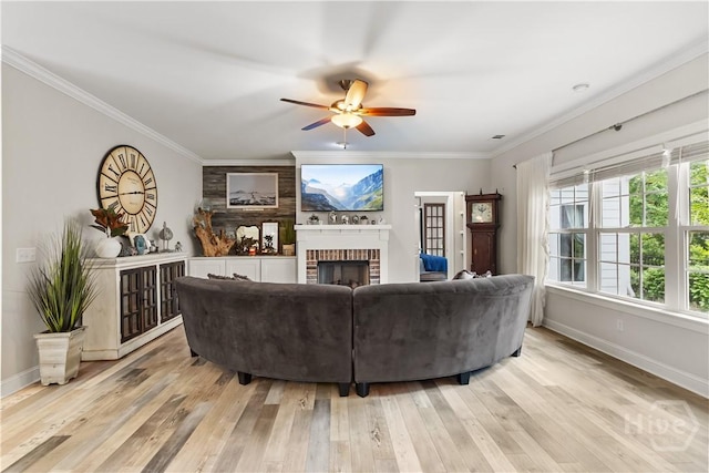 living area featuring a fireplace, baseboards, ceiling fan, light wood finished floors, and ornamental molding