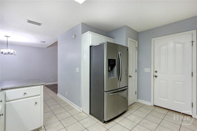 30 Bridgewater Way, Brunswick, GA 31525 - kitchen with stainless steel fridge, light tile patterned floors, white cabinetry, and baseboards