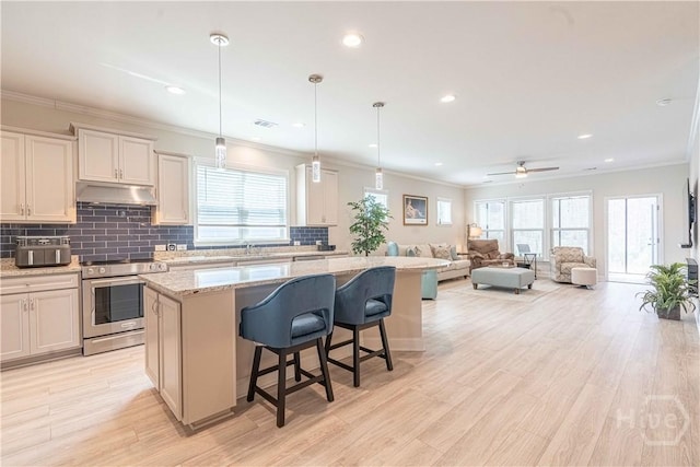 137 Harvest Hl, Pooler, GA 31322 - kitchen featuring electric stove, under cabinet range hood, a kitchen island, decorative backsplash, and a kitchen breakfast bar