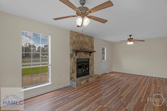 1021 Bacon Rd, Hinesville, GA 31313 - unfurnished living room featuring ceiling fan, healthy amount of natural light, wood finished floors, and a stone fireplace