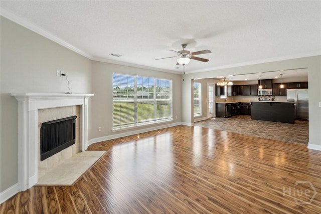 1107 Creekside Cir, Hinesville, GA 31313 - unfurnished living room with wood finished floors, ceiling fan, a tiled fireplace, baseboards, and crown molding