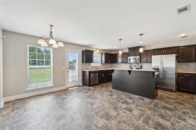 1107 Creekside Cir, Hinesville, GA 31313 - kitchen with stainless steel appliances, light countertops, dark brown cabinets, a chandelier, and a textured ceiling