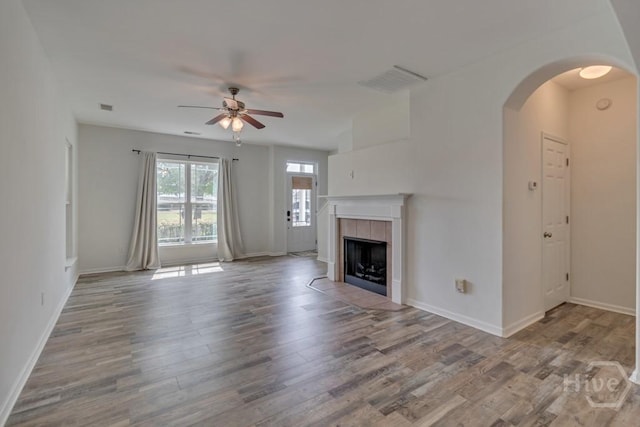 48 Chapel Lk N, Savannah, GA 31419 - unfurnished living room with ceiling fan, wood finished floors, arched walkways, a tiled fireplace, and baseboards